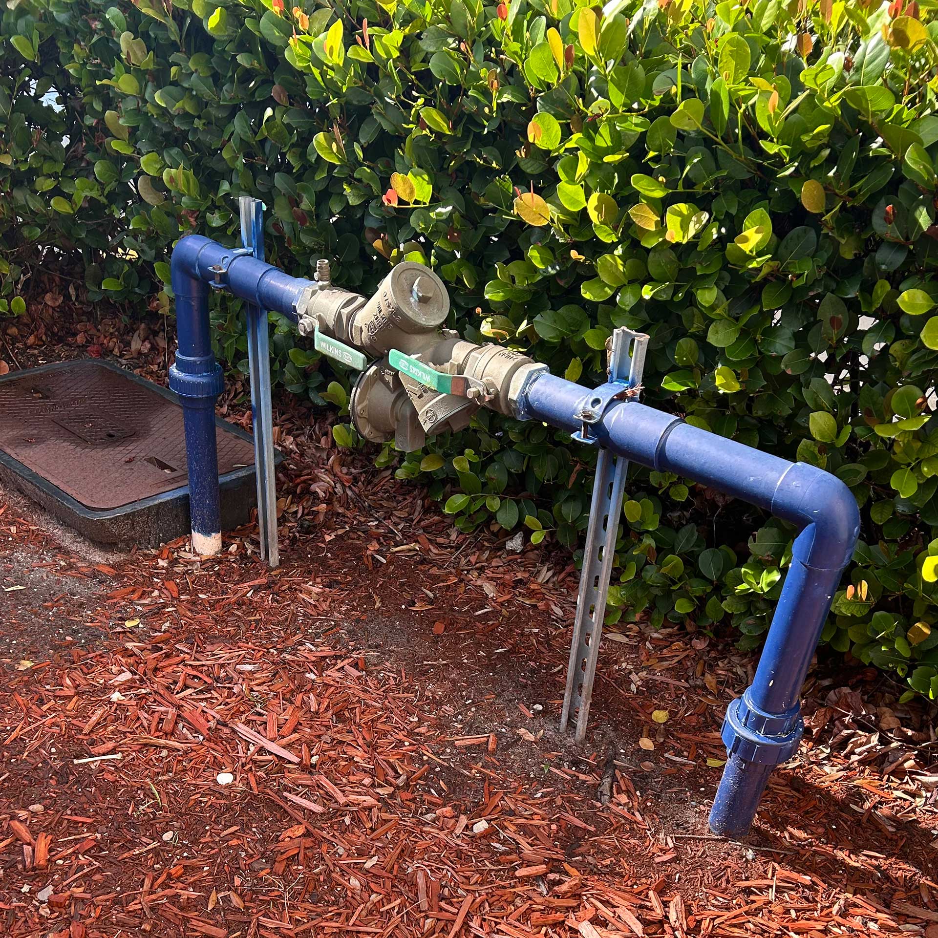 A backflow preventer beside a water meter box.